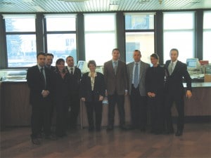 Sopra, una foto dello staff della sede distaccata di Buguggiate assieme ai due direttori. A sinistra, la stretta di mano tra Roberto Gentilomo (a destra) e Luca Giardini nuovo direttore di Buguggiate.